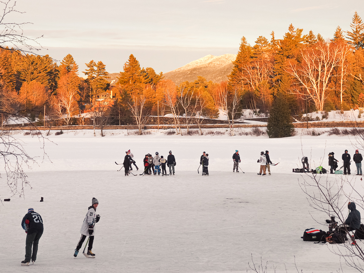 Children playing ice hockey on Lake Placid with a stunning mountain view in the back