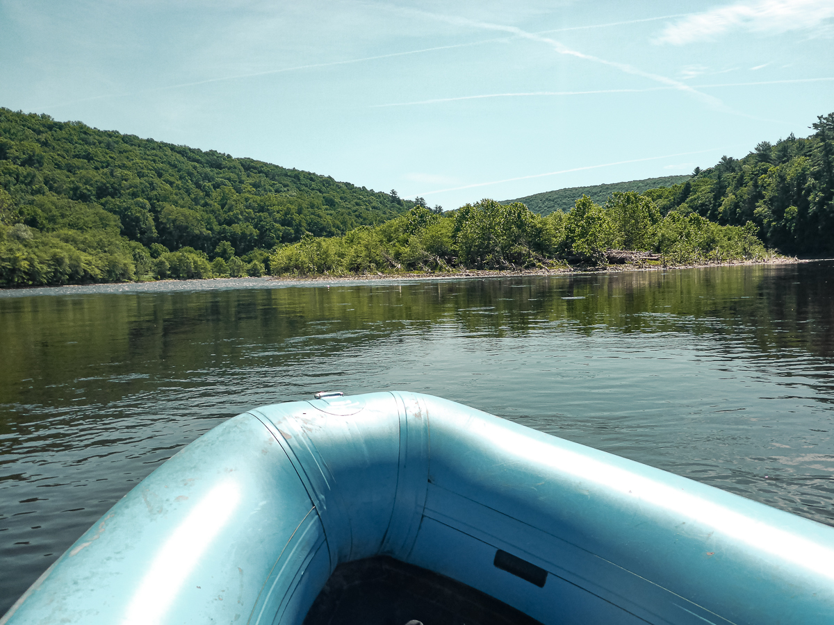 Floating in the Delaware River with our blue raft, surrounded by green forests