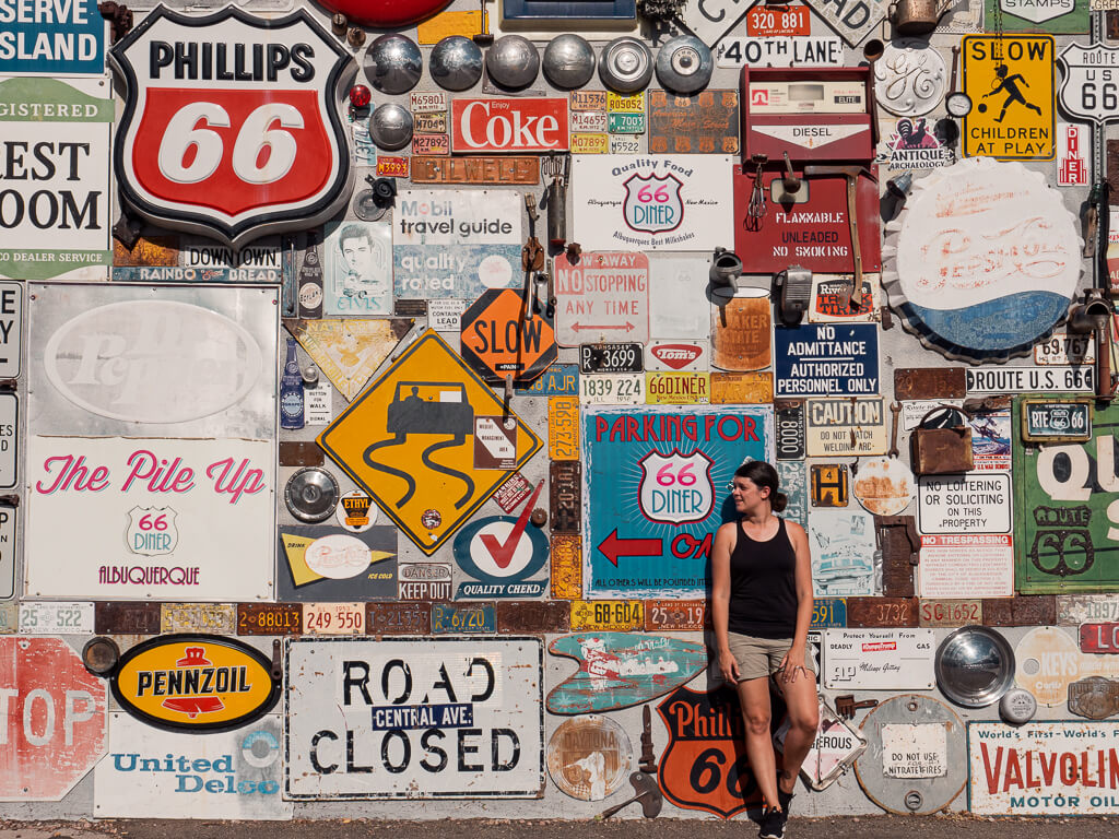 Dana standing in front of a wall of license plates and signs