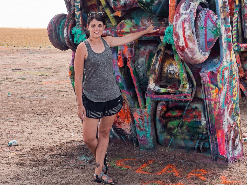 Dana standing in front of a spray painted Cadillac at Cadillac Ranch